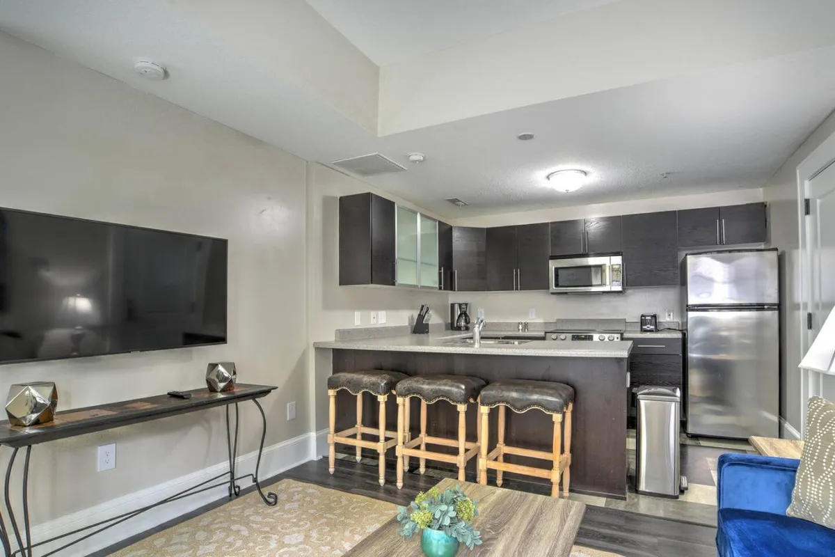 A view that combines the kitchen area with an adjacent living room, highlighting open-plan living. The kitchen is visible alongside comfortable seating and a television, creating a casual, cozy atmosphere ideal for both dining and relaxing.