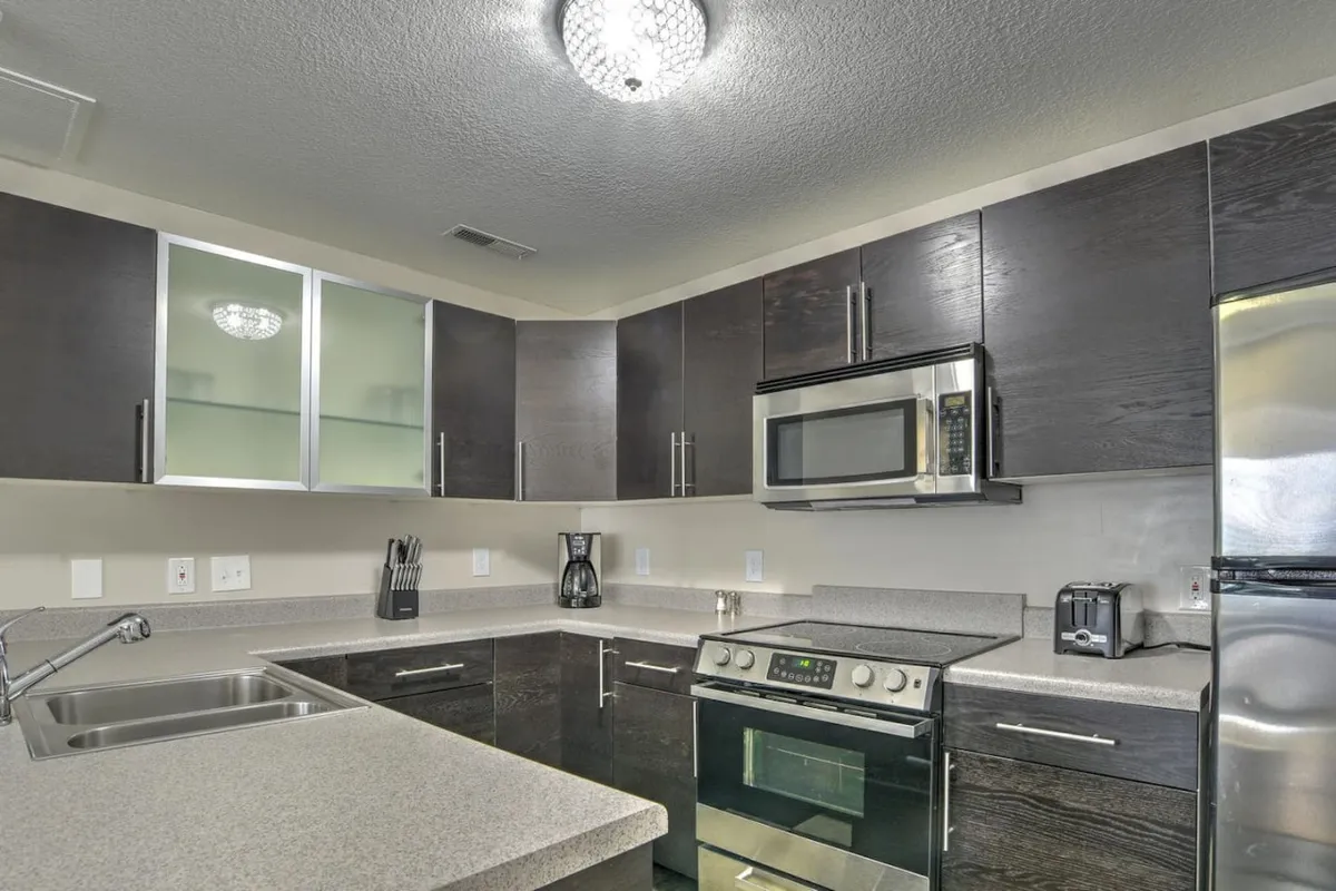 This image features a modern kitchen complete with stainless steel appliances, granite countertops, stylish cabinetry, and a decorative light fixture. The space feels contemporary and inviting, perfectly suited for both cooking and entertaining.